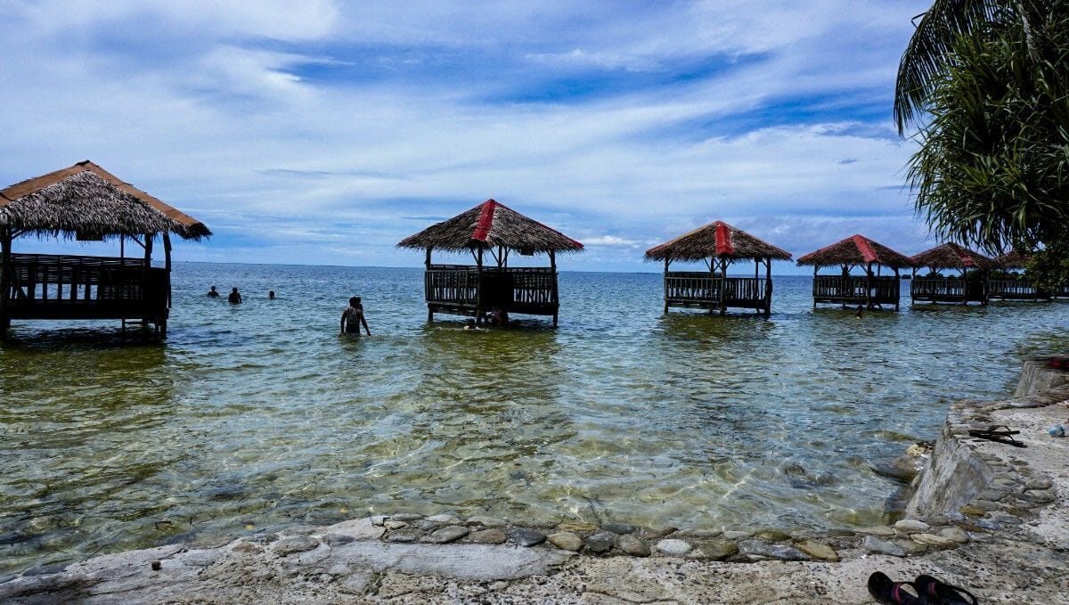 Orilla con casitas locales para disfrutar del sonido del mar, experiencia que vivirás viajando a Filipinas