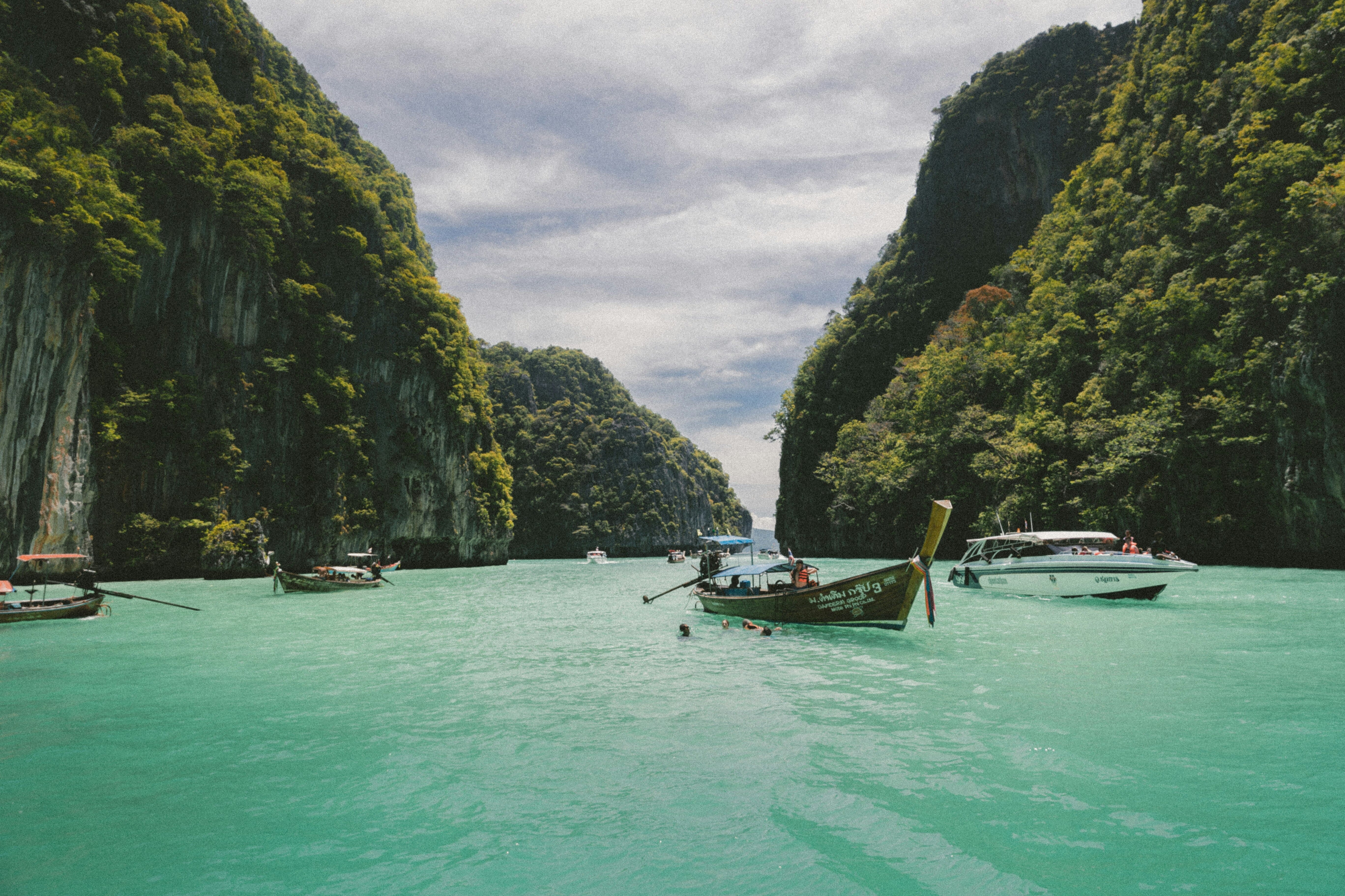 Barco tradicional remando en Ko Phi Phi, Tailandia, entre aguas turquesas y acantilados de piedra caliza, paisaje tropical ideal para viajes y turismo a Tailandia